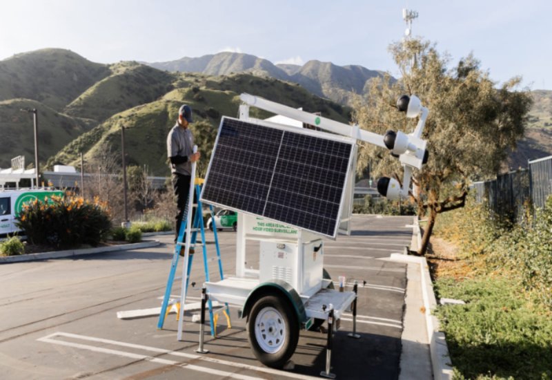 Man on ladder repairing trailer-mounted security system in Austin and Dallas, Texas
