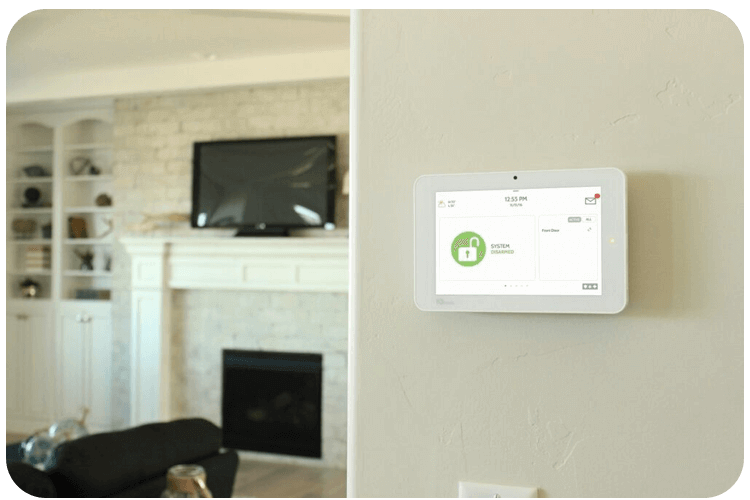 A home security panel mounted on a wall in a living room with a fireplace and TV in Phoenix, AZ.