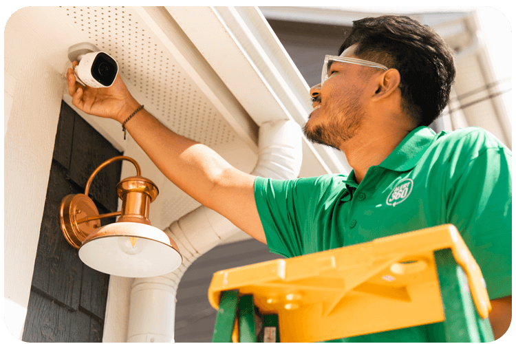A professional is installing a home security system outside of a house in Austin and Dallas, TX.